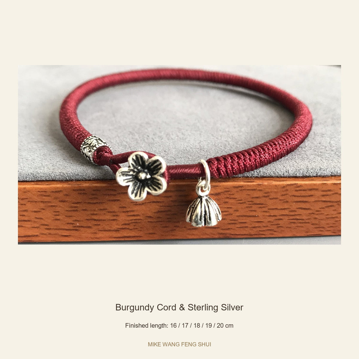 Burgundy woven cord bracelet with a floral silver clasp and lotus-pod charm