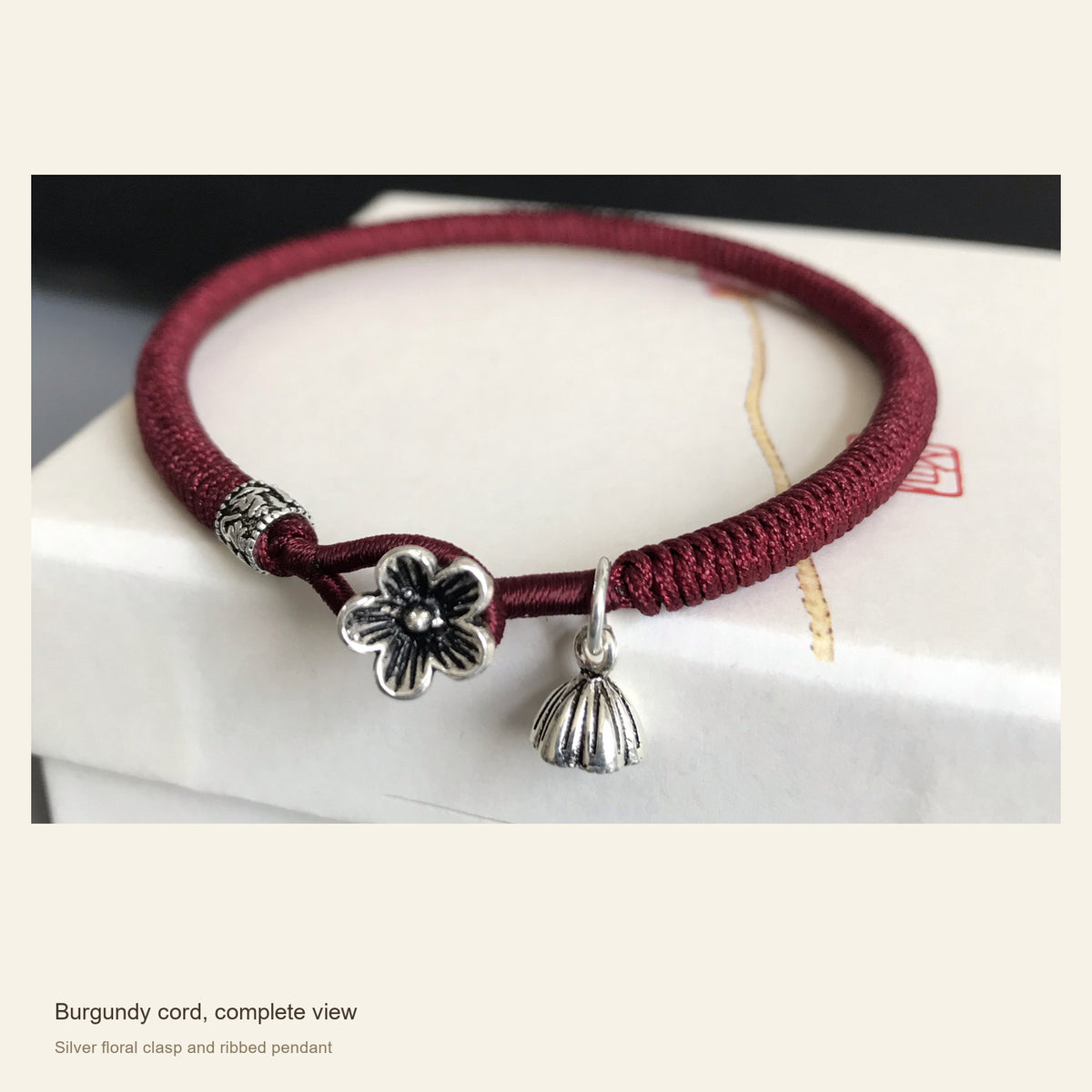 Burgundy Red Cord Bracelet with Sterling Silver Floral Clasp — Burgundy cord, complete view; Silver floral clasp and ribbed pendant