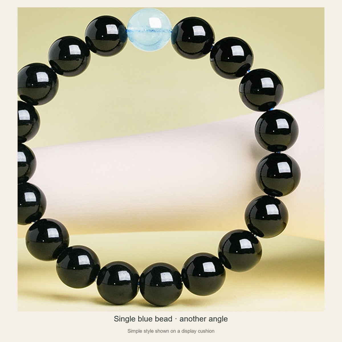 Simple obsidian and aquamarine bracelet on a cushion, second full angle